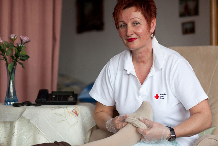 Ambulante Pflege 01 Deutsches Rotes Kreuz DRK, Einsatzbereiche / Aktivitaeten / Leistungen / Aufgaben, Sozialarbeit, Ambulante Pflege Hauspflege haeusliche Pflege, Strumpf, anziehen, Einmalhandschuhe, Betreuung